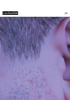 In Nahaufnahme ist ein männlicher Haaransatz am Ohr zu erkennen, ebenso ein paar Bartstoppeln.
