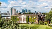 Ein altes Gebäude mit Efeu prangt in der Bildmitte. Dahinter reihen sich die Wolkenkratzer und Bürogebäude Londons auf.