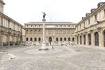 Zu sehen ist eine dreiflügelige Anlage,. In der Mitte des umfassten Platzes steht eine Säule mit einer Bronzestatue darauf. Der Platz heißt Cour Bonaparte