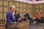 Martin Köttering, President of the HFBK, stands at the lectern and speaks. The participants of the first panel can be seen in the background. 