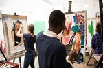 In einem Atelier schaut der Betrachter Studierenden über die Schulter während diese an Staffeleien stehen und malen.