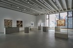 Ausstellungsobjekte jeglicher Art stehen und hängen im Ausstellungsraum. Vitrinen und Plexiglaswände stehen auf Betonsockeln. Das Licht ist gedimmt. Insgesamt herrscht ein musealer Charakter.