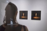 Verschwommen in der linken Bildhälfte ist eine Frau in Rückenansicht zu sehen. Sie schaut sich das Werk "Selbstverantwortung" bestehend aus drei Akt-Fotografien an.