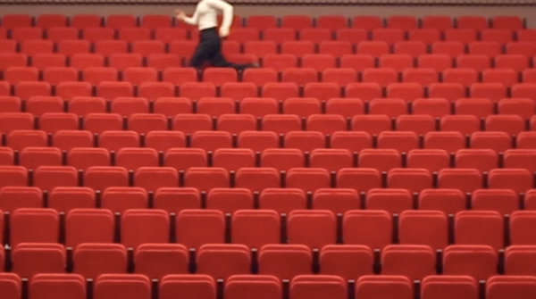 Rote Kinositze. Oben am Rang läuft eine Person entlang.