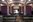 Ein Blick in die leere Mensa der HFBK: schwarze Holztische und -bänke mit grünen Sitzflächen, ein violetter Vorhang trennt den Gastraum von der Essensausgabe. Ganz hinten im Bild sind die schwarzen und türkisfarbenen Fliesen des Gastrobereichs zu sehen.