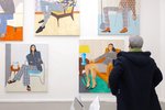 A person stands in front of a wall with colored portrait paintings