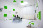 People sitting on a transparent plastic chair in a white/green environment
