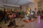 People sit on the floor and listen to a person who is standing at the microphone reading something out loud.