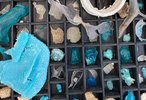 Ein Setzkasten wurde von oben fotografiert, er enthält Steine, Bruchstücke, organische Materialien. Die meisten von ihnen in Blau, Türkis, Beige.