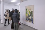 Besucher*innen einer Ausstellung schauen sich ein großformatiges Gemälde an mit einer abstrakten Figur darauf. Andere Besucher*innen bewegen sich in dem weißen Ausstellungsraum.