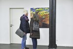 Zwei Besucer*innen stehen vor einem Gemälde und reden miteinander. Sie tragen Winterjacken und Taschen. Auf dem Gemälde ist ein farbiger Mann zu sehen, der mit geschlossenen Augen Musik hört.