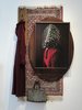 Mehrere Objekte hängen überlagert voneinander an der Wand. Ein Teppich, ein Samtmantel, eine Handtasche mit Nieten, ein Bild auf einer ovalen Holzplatte angebracht.
