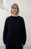Eine Frau mit schulterlangen blonden Haaren steht locker in einem Oversize-Pullover und weißem Shirt darunter in die Kamera. Sie scheint in dem schwarzen Pullover unter zu gehen.