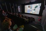 Eine dunkler kleiner Kinosaal mit vollbesetzten Besucherraum. Auf der Leinwand läuft ein Film.