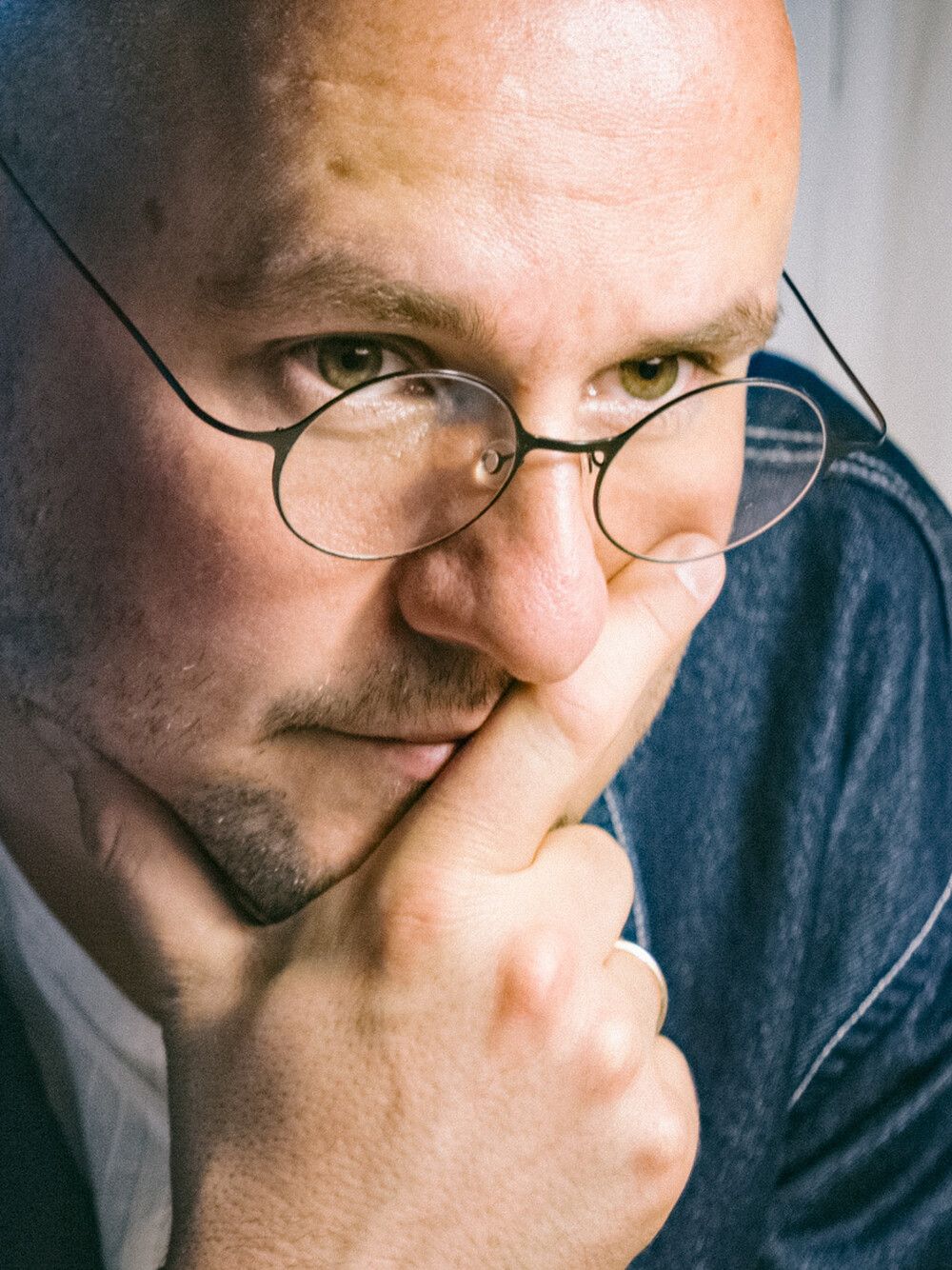 Portrait of a man wearing glasses, with the top of his head slightly cropped at the upper edge of the image.