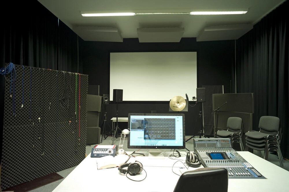A view into a room with a computer and a projection screen, with fabric and acoustic panels on the walls.