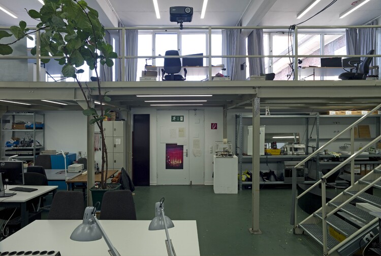 A high-ceilinged room with a gallery and several workstations
