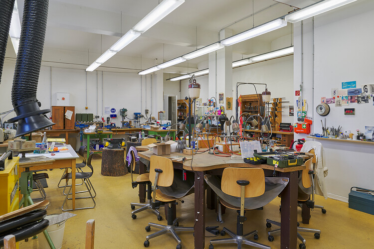 “Many chairs around a table, an air duct hangs into the room, tools everywhere.”