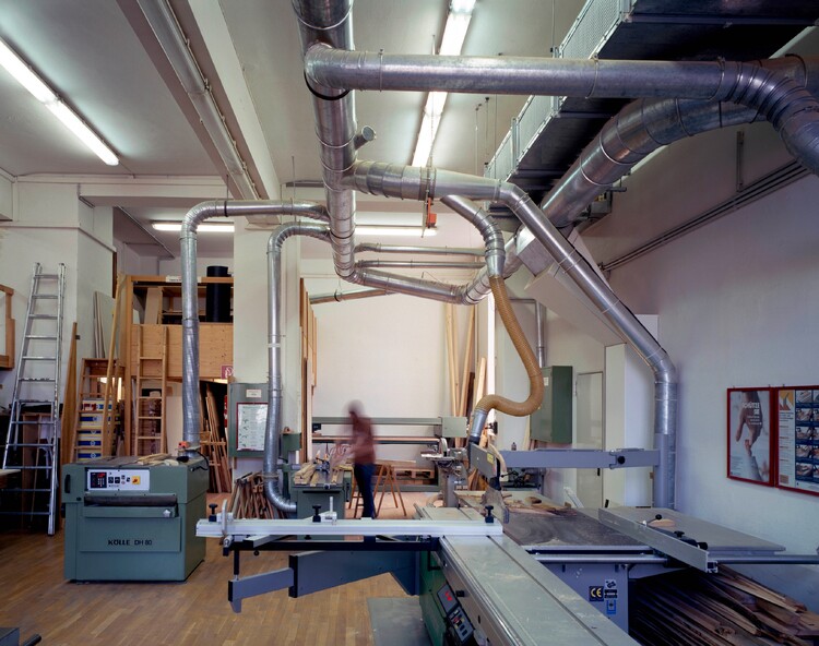 Large wood saws and exhaust pipes in a high room, one person working