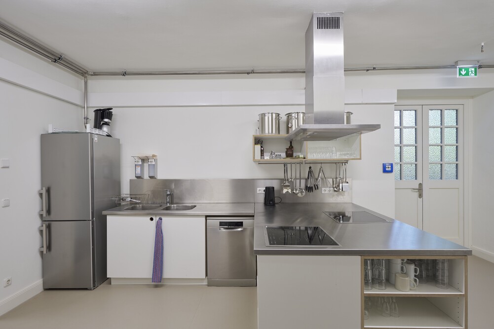 A kitchenette with a refrigerator, sink, stove, and extractor hood.