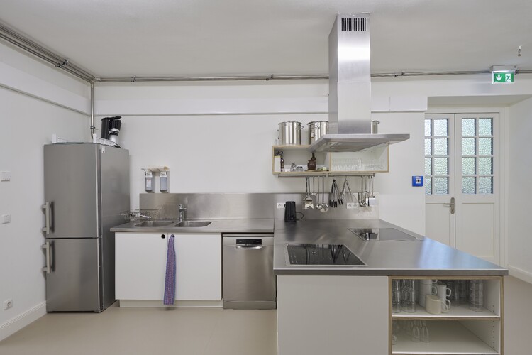 A kitchenette with a refrigerator, sink, stove, and extractor hood.