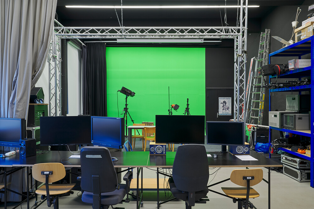 A room with trusses, green wallpaper hanging from the ceiling, and accessories on a shelf at the side.