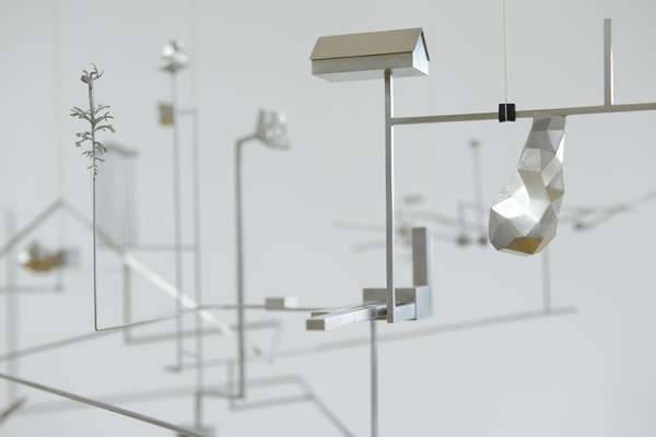 On a delicate steel framework with many branches, small objects are attached, like a little house.